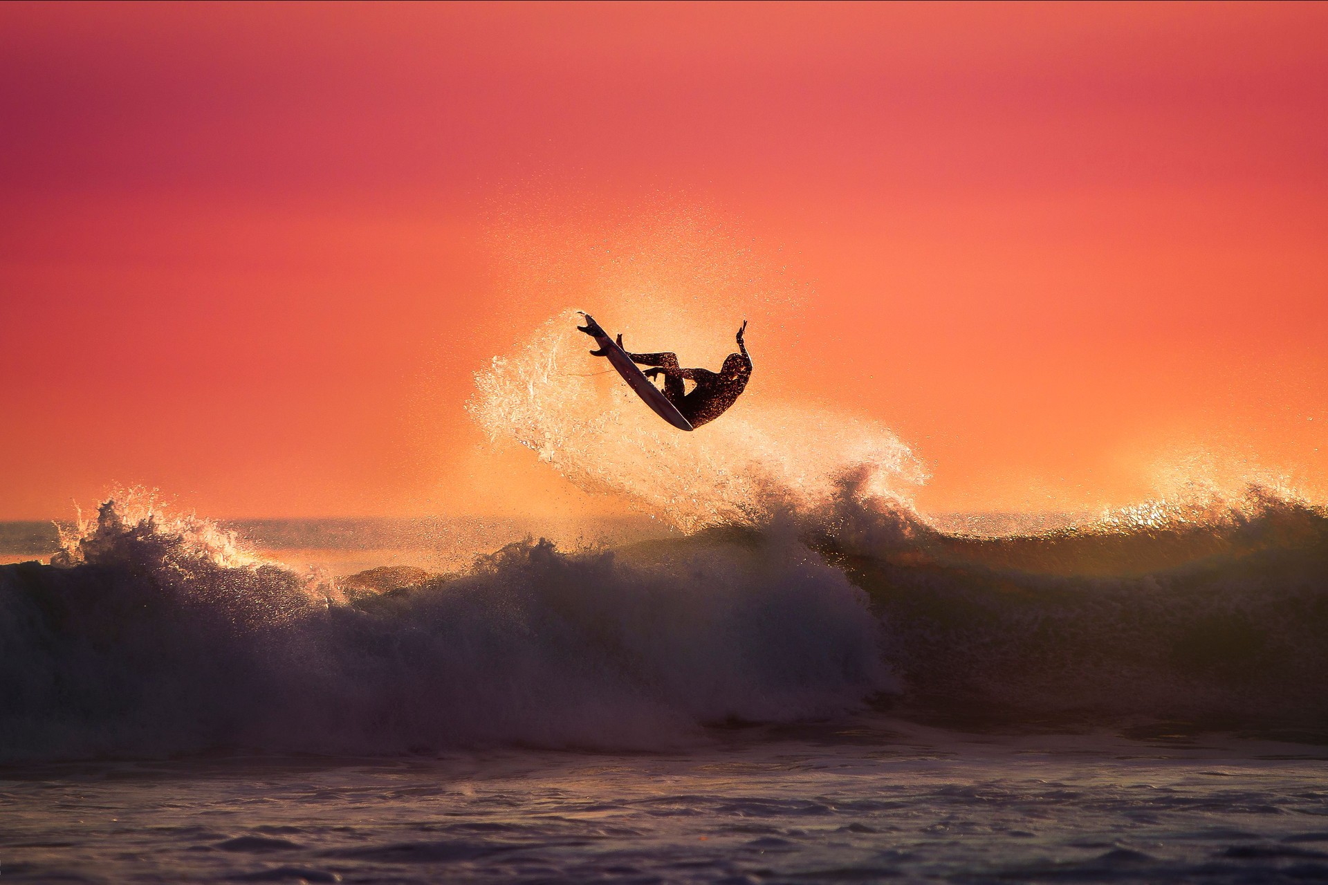 Surfer jumping on top of a Wave